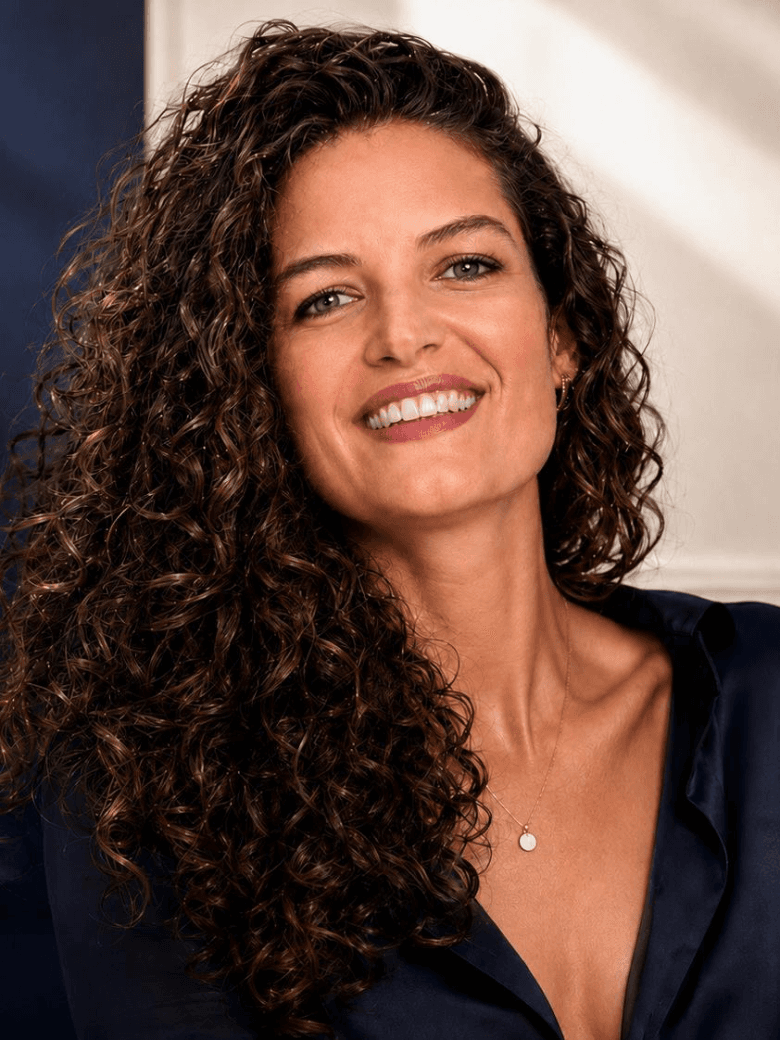Manuela, enseignante de français, souriante, chemisier bleu nuit et fine chaîne dorée